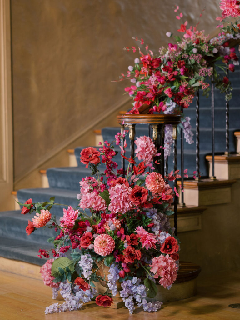 Magenta floral installation on staircase of historic museum.