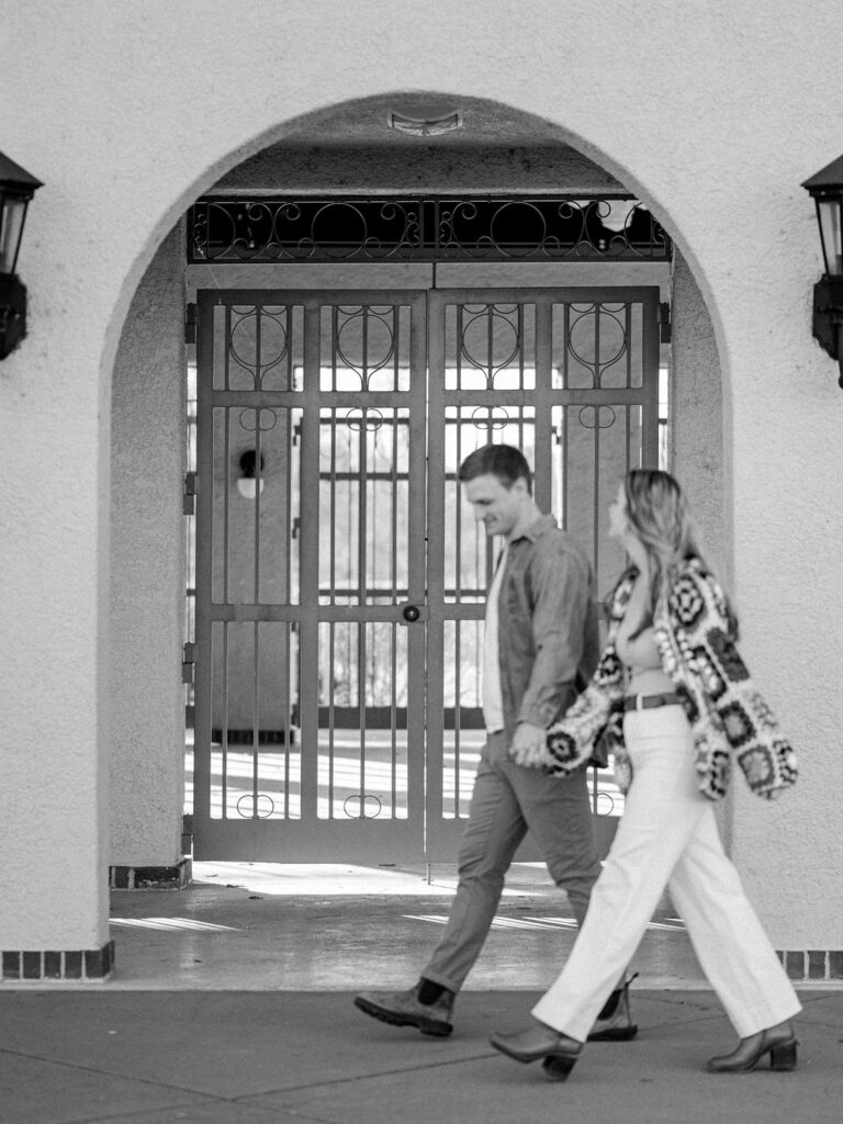 A couple walks in front of a gated archway at City Park in Downtown Denver.