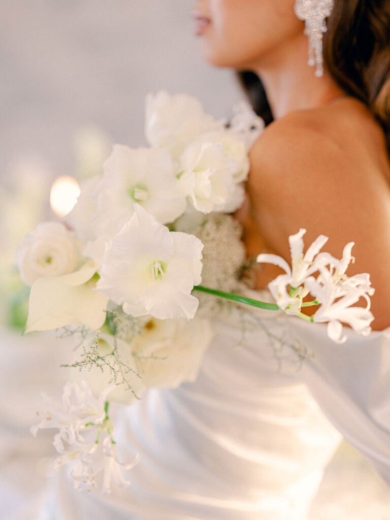 A close up of a bride holding a bouquet of elegant white flowers.