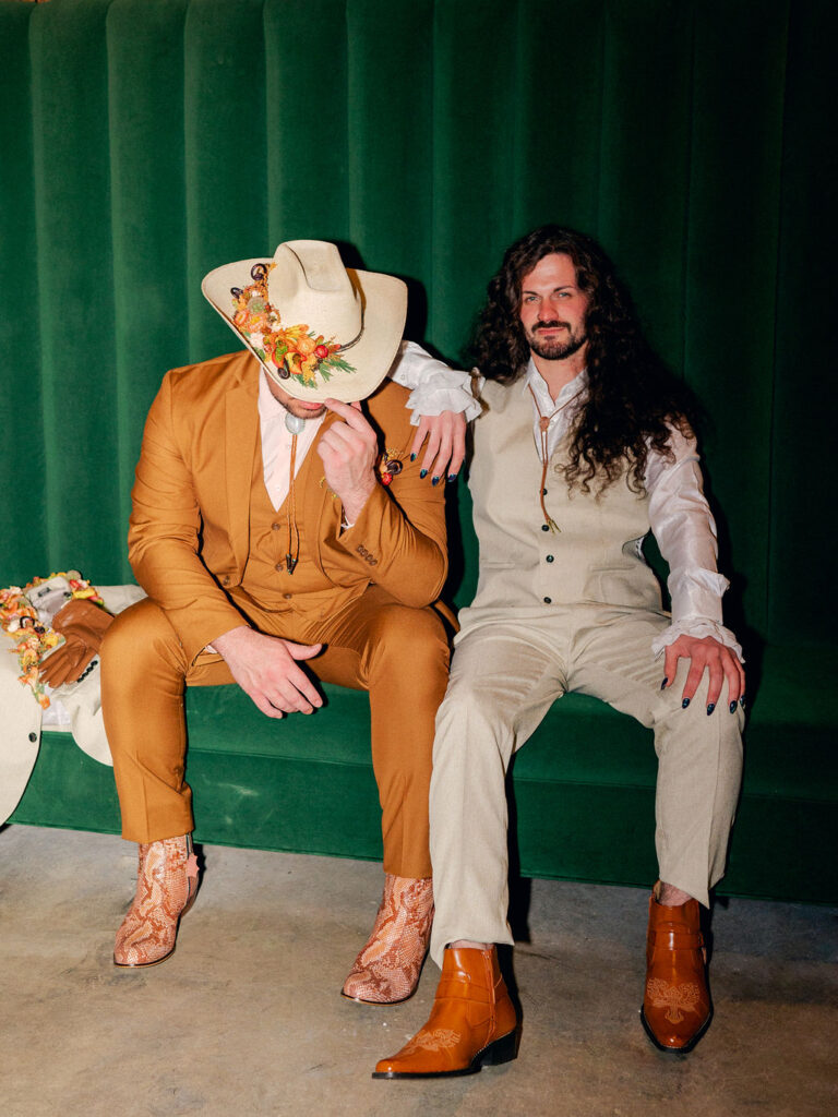 Two grooms sit at the bar in a basement speakeasy for a western inspired LGBTQ wedding in Boulder, Colorado.