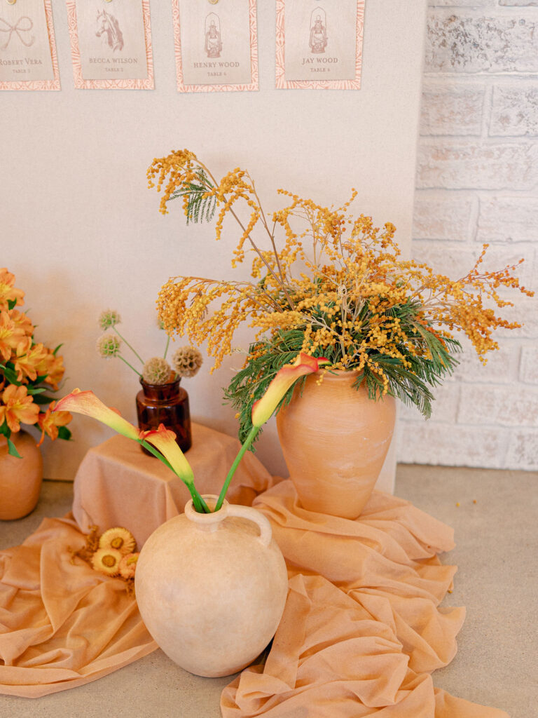 Orange florals in terracotta vases at a western inspired LGBTQ wedding in Colorado.