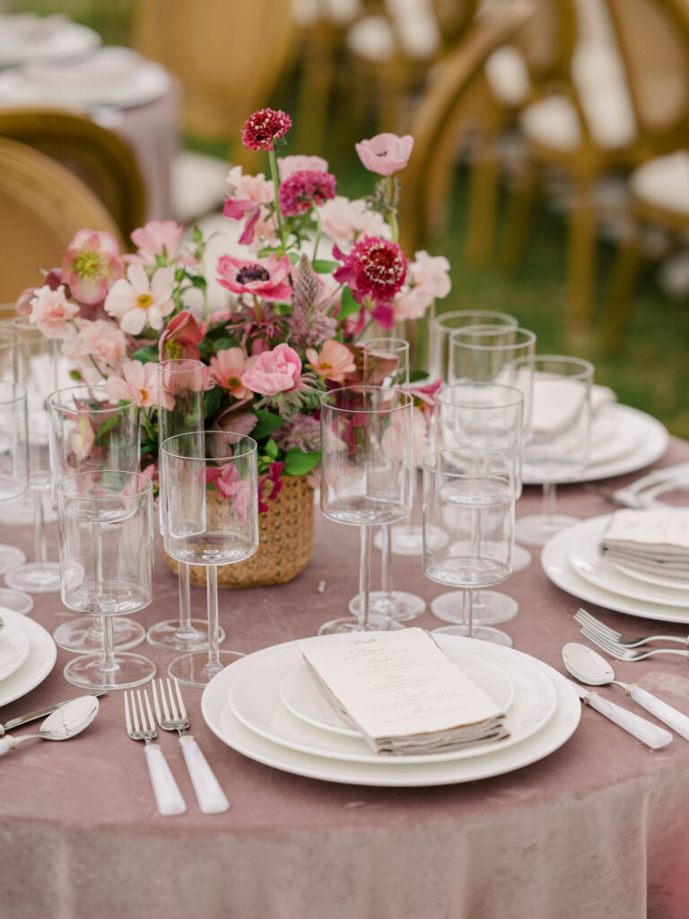 Wedding reception place setting with modern dishware, letterpress menus, and pink floral centerpiece.