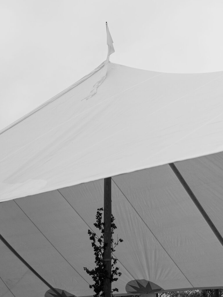 Flags on top of wedding sperry tent blow in the Oklahoma wind.