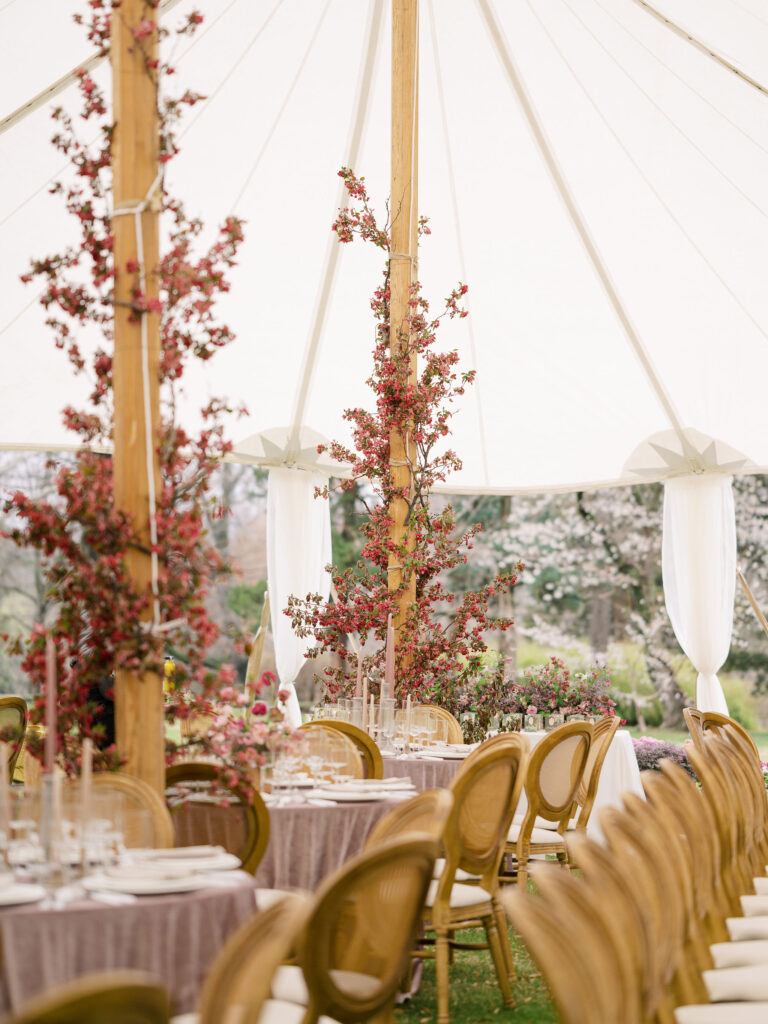Tented wedding reception with florals winding up support beams and velvet table cloths.