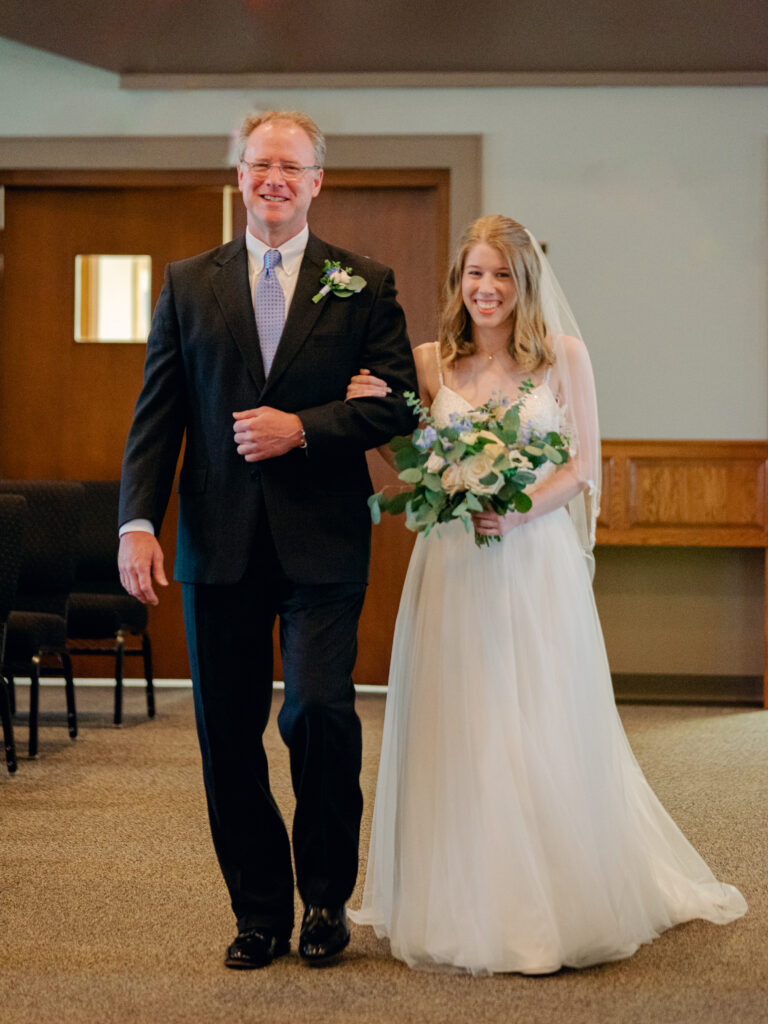 Bride and her father walk down the aisle of the church.