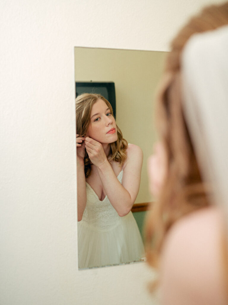 Bride puts on her earrings as she gets ready for her wedding.