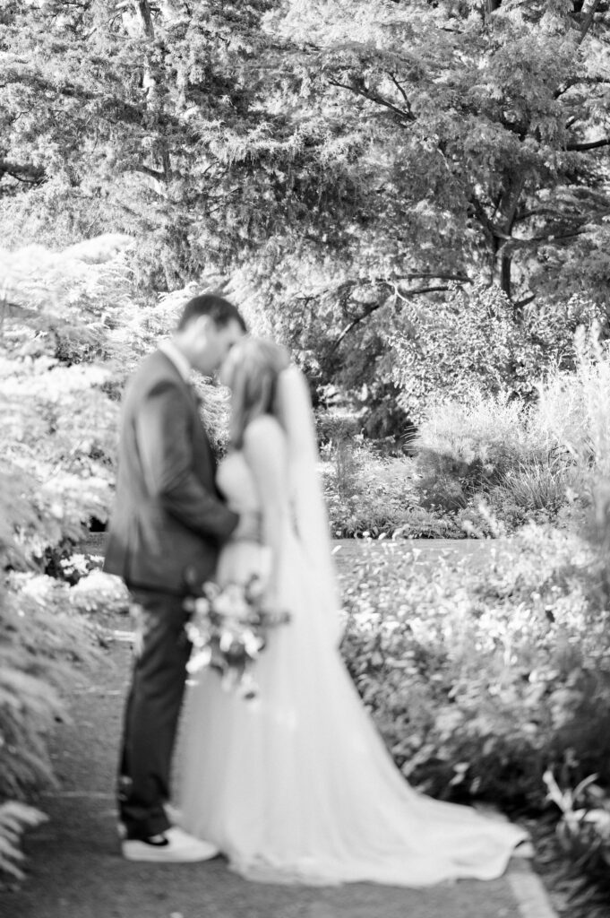 Bride and groom kiss in black and white portrait in garden intimate elopement.