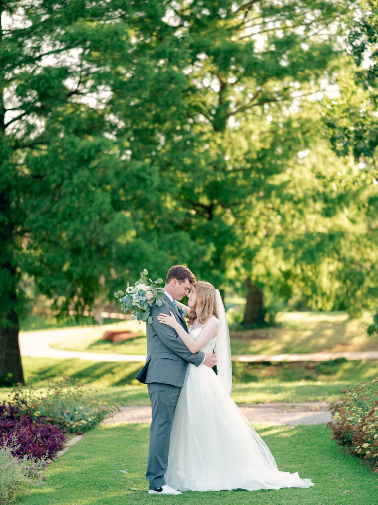 Bride and groom kiss in garden during wedding portraits.