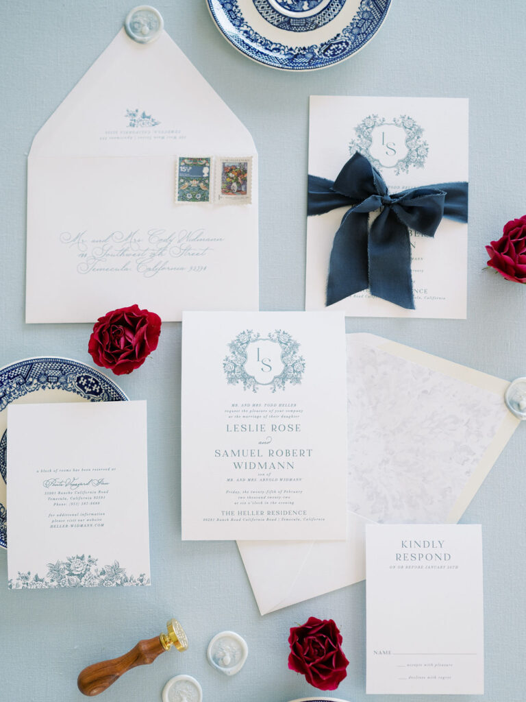 Blue and white wedding invitation suite with floral illustrations.