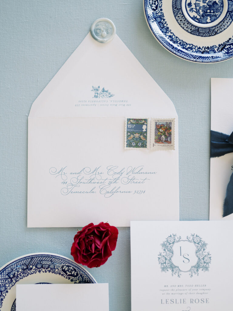 Blue and white wedding invitation suite with floral illustrations.