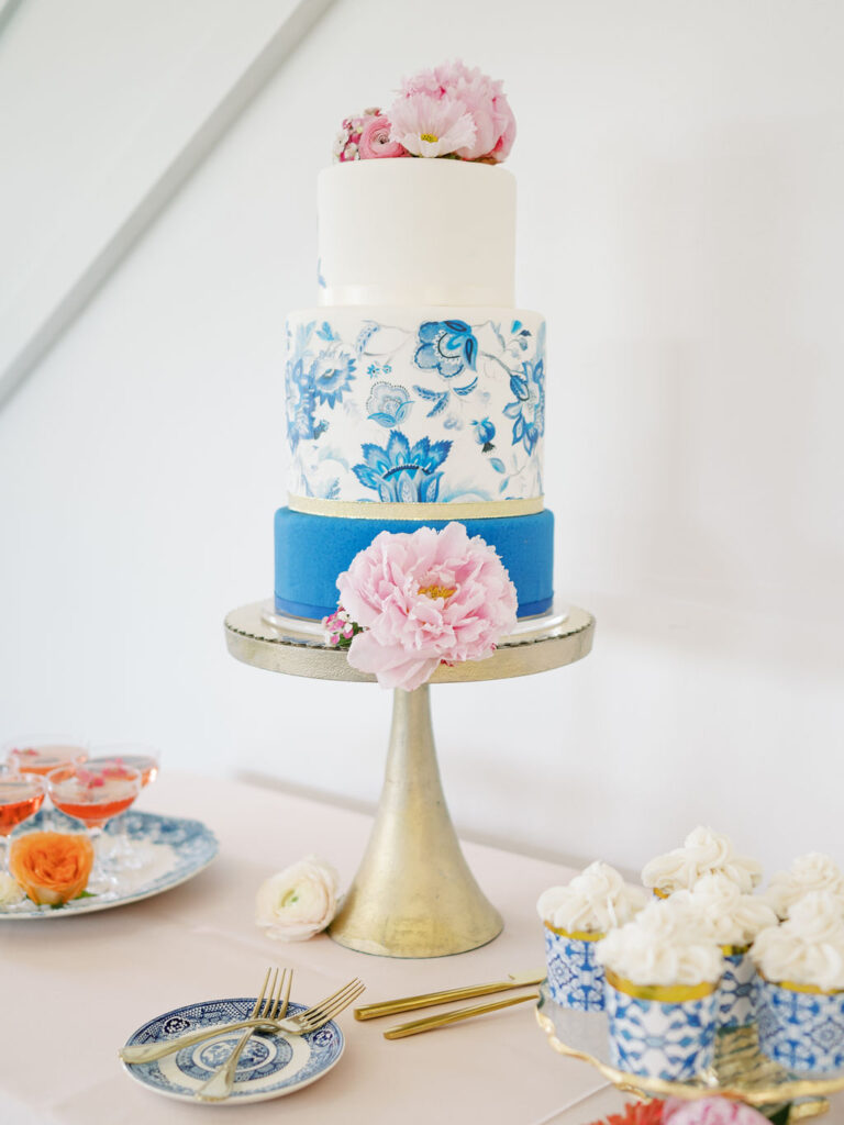 A three tier blue and white wedding cake with a floral pattern printed on the second tier.