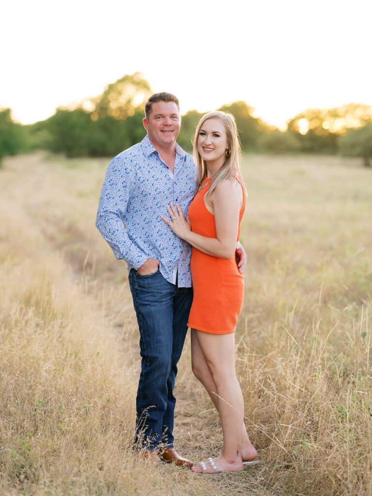 Formal portrait of couple in an open field at sunset