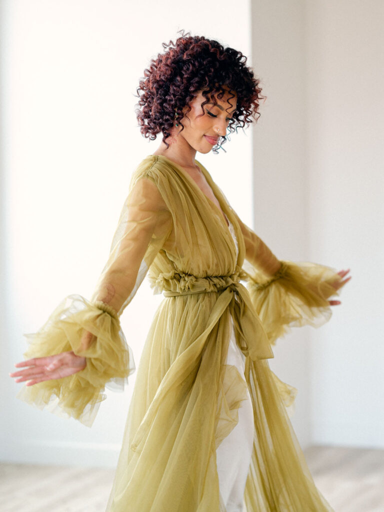 A bride wears a dramatic green ruffled robe while getting ready.
