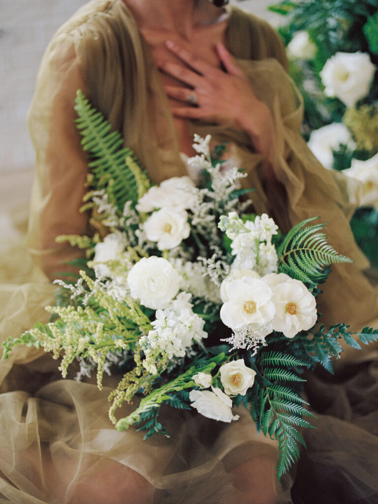 A bride sits with her wedding bouquet in a dramatic green ruffled robe.
