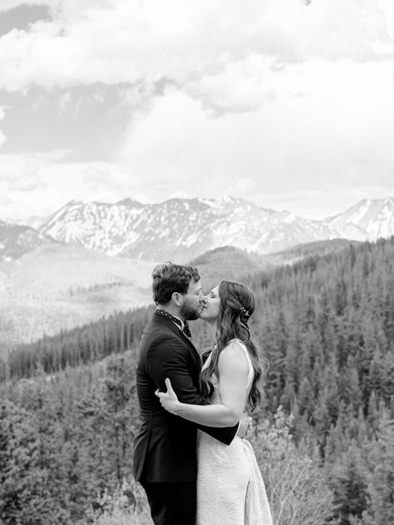 A bride and groom share a kiss among the mountains in Vail, Colorado.