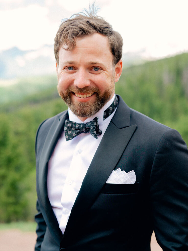 A groom smiles in a classic portrait on a summer day in Vail, Colorado.