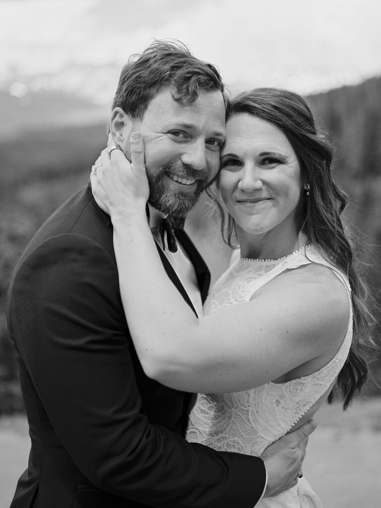 A bride and groom smile at the camera in a classic black and white wedding portrait in Vail, Colorado.