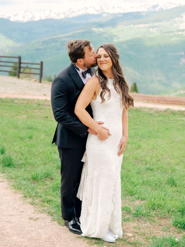 A groom hugs his bride from behind in a sweet wedding portrait in Vail, Colorado.