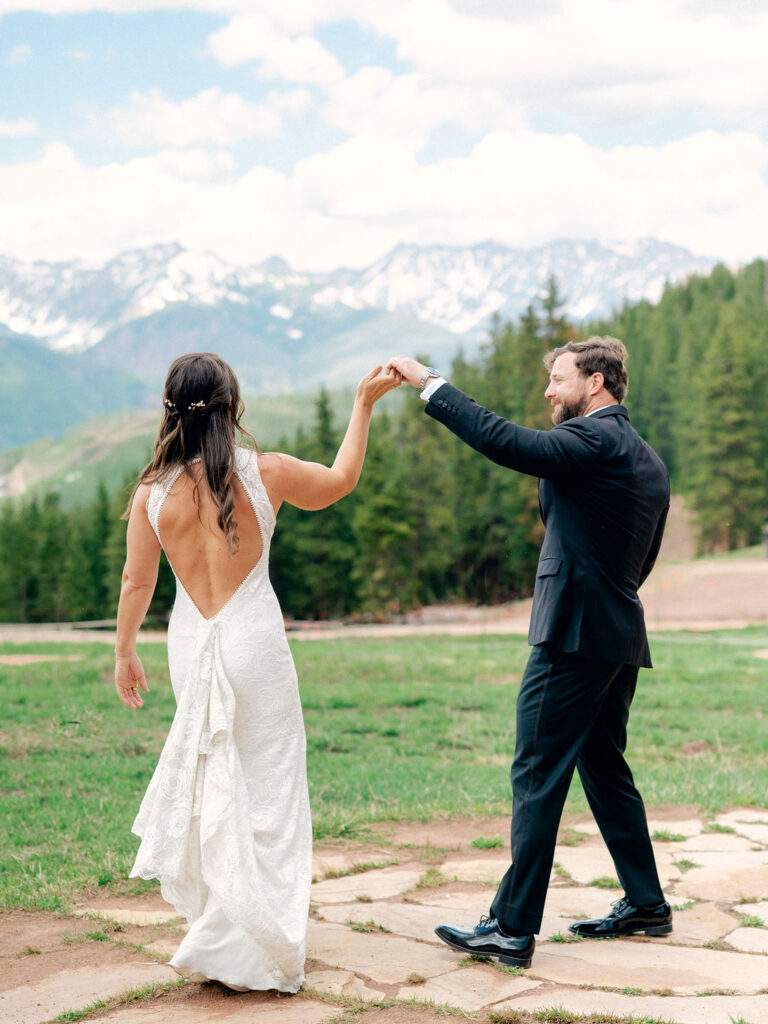 A groom twirls his bride on a sunny day at Vail Mountain.