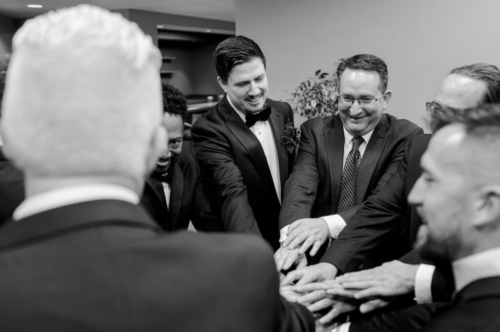 A groom and his groomsmen put their hands together and cheer just before his Oklahoma City wedding ceremony.