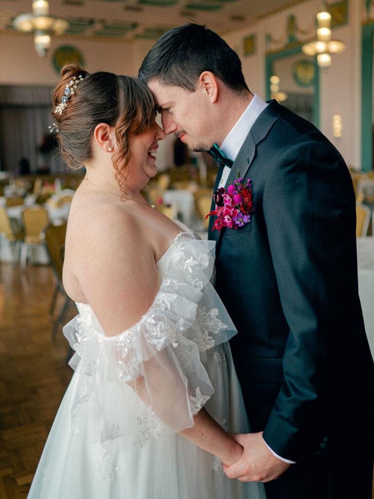 A bride and groom hold hands and look at each other in their art deco wedding venue, the OKC Civic Center Hall of Mirrors.