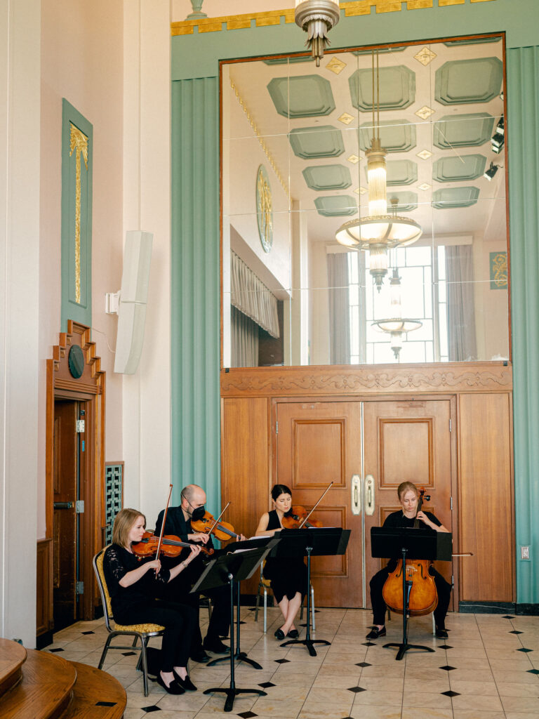 A string quartet plays in a teal and gold art deco wedding venue in Oklahoma City.