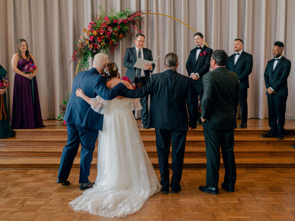 A bride is given away by her brothers at the end of the aisle during her wedding ceremony.