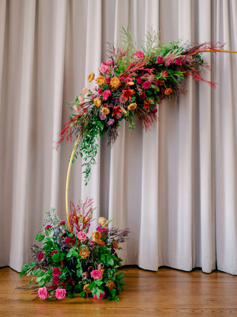 A gold arch covered in jewel tone florals for an Oklahoma City wedding ceremony.