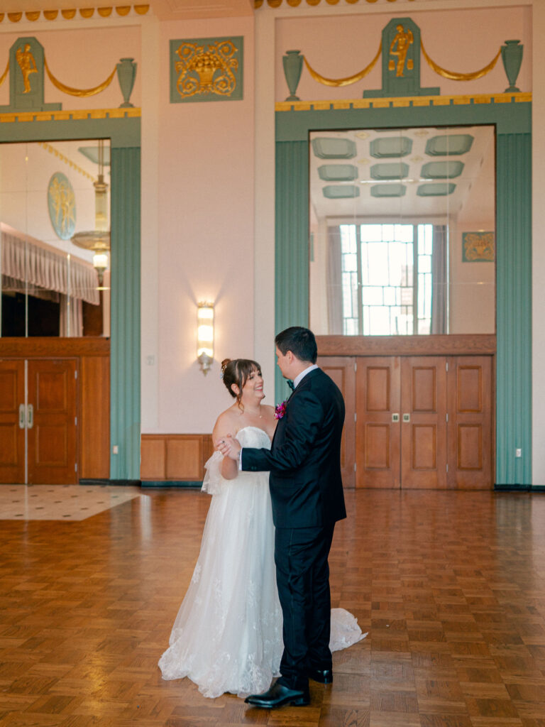 A bride and groom have their first dance in a teal and gold art deco wedding venue in Oklahoma City.