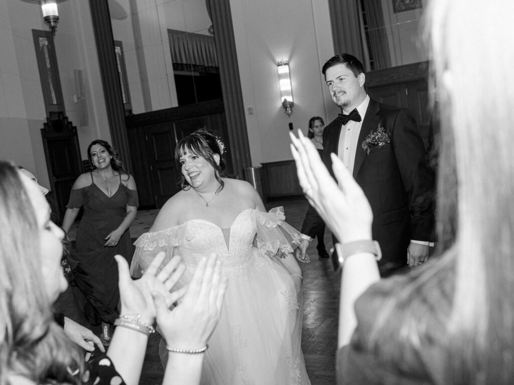 A bride and groom dance with their guests at their wedding reception.